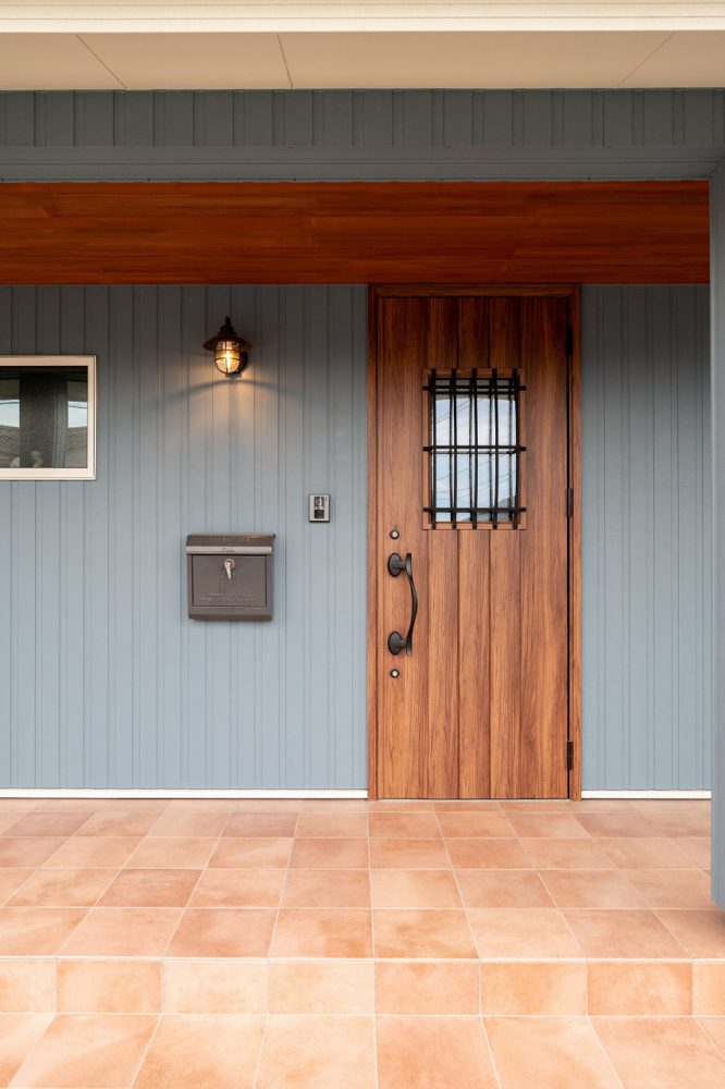 ブルーグレーの外壁と木目扉の玄関